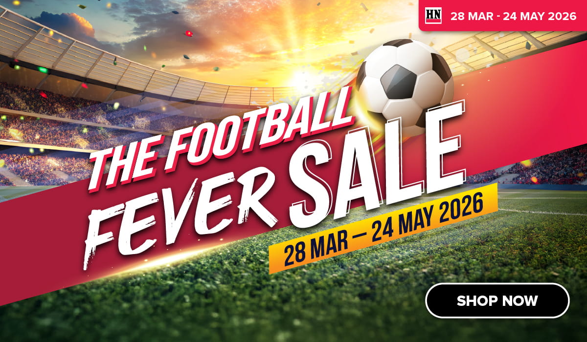 Man in a gray blazer over a dark gray shirt standing on stairs in an urban background.