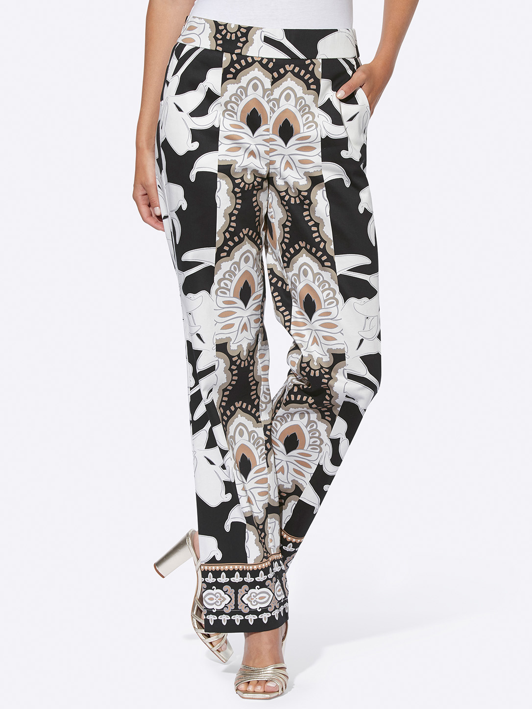 Damenhose mit weitem Bein, schwarz-weiß-beigem floral-abstraktem Muster, kombiniert mit silbernen High-Heels.