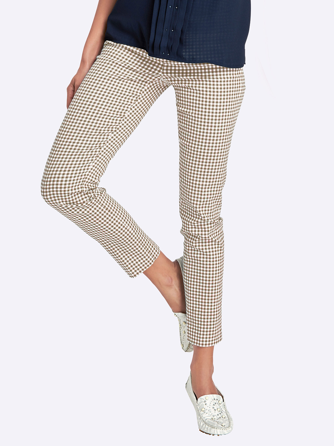 Damenhose mit engem Schnitt, braun-weiß kariert, kombiniert mit weißen Mokassins und dunkelblauem Oberteil.