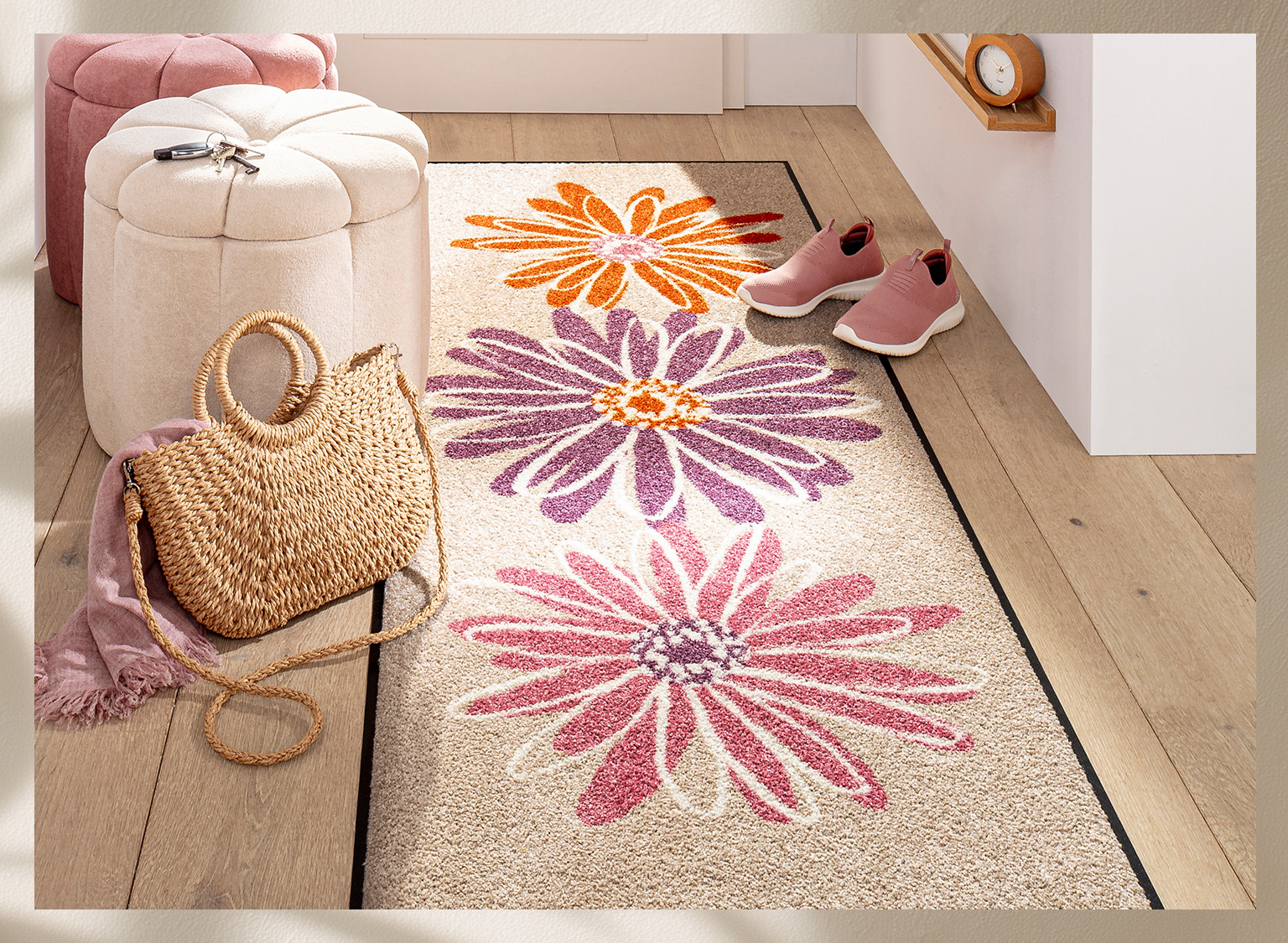 Heller Flur mit Läufer, der große Blumen in Orange, Lila und Pink zeigt. Daneben Korbtasche, rosa Schuhe und Sitzhocker.