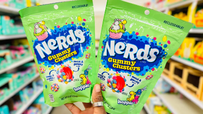 a hand holding two bags of nerds candies in a grocery store