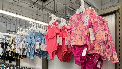 Assortment of childrems swimsuits in varying sizes hung on a wall rack