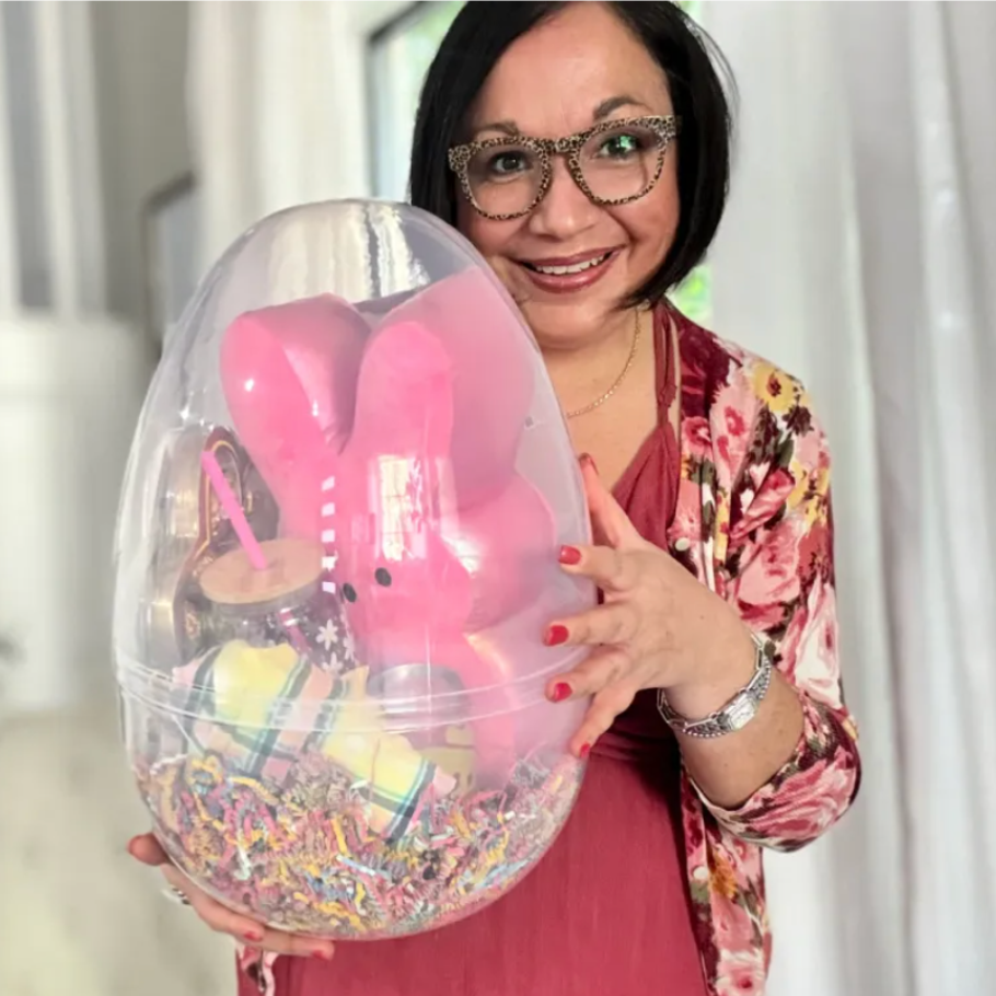 a woman holding a giant clear plastic egg with toys inside