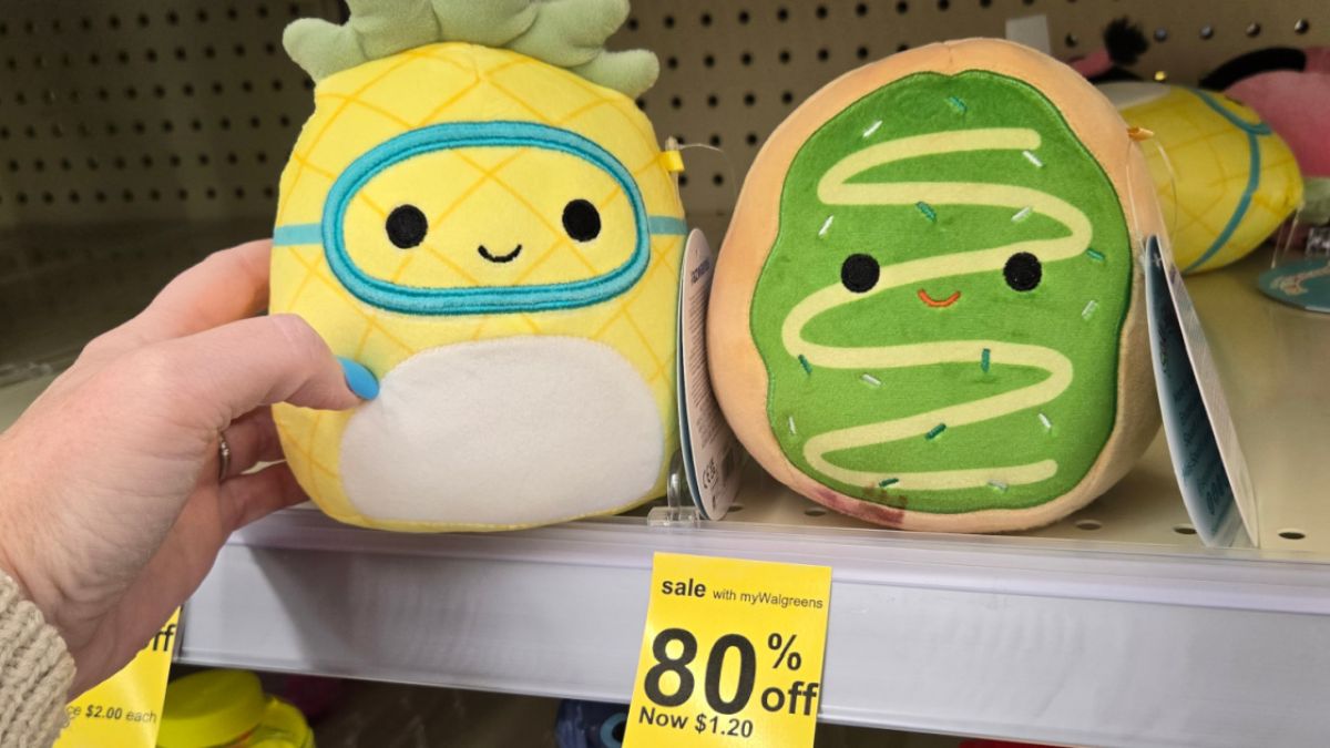 hand pulling a squishmallow plush off a clearance shelf of other toys