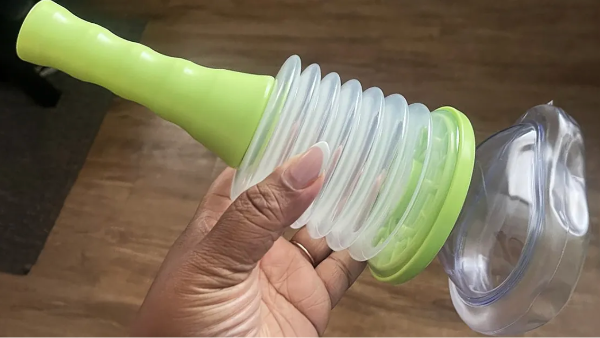 a hand holding a green blender with its lid open