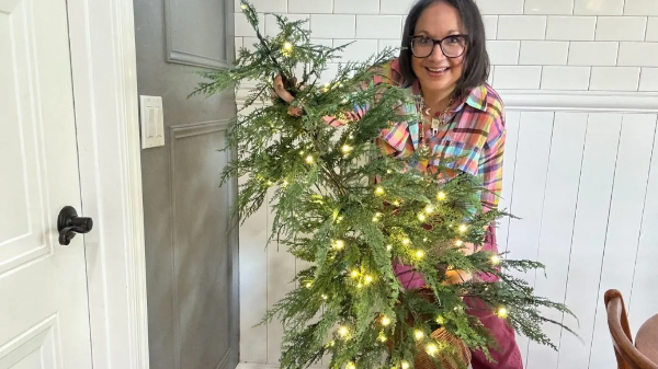 woman holding a green pre-lit cypress style christmas tree