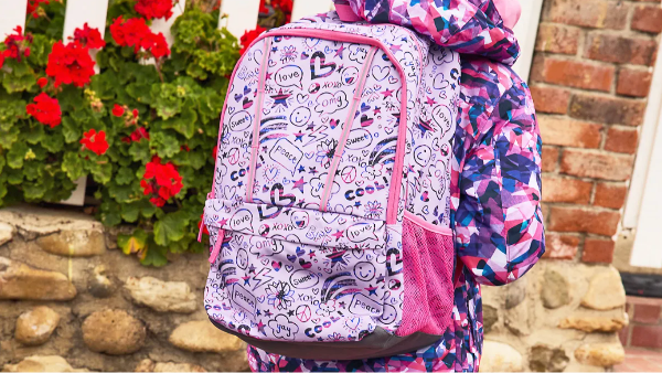 Child searing a pink and purple patterned backpack with a side pocket