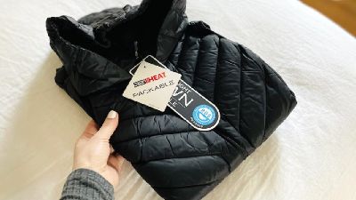 folded black jacket on a bed