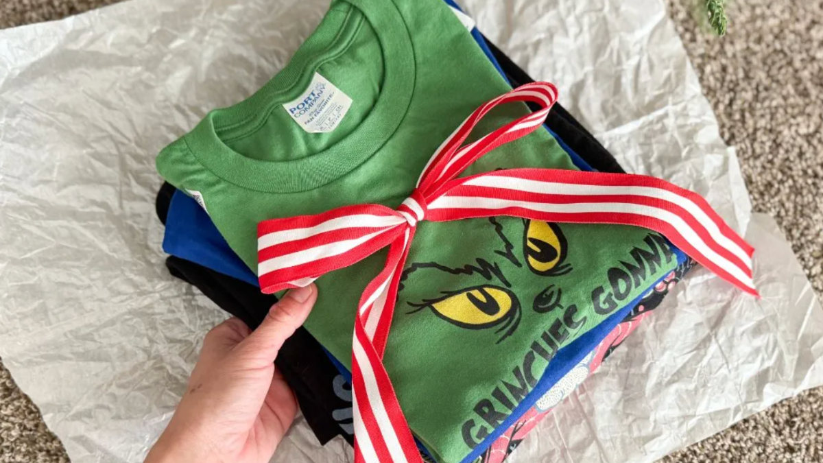 Stack of folded T-shirts on top of white tissue paper with red and white ribbon