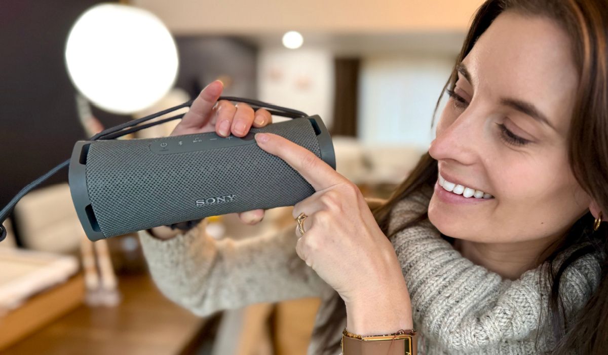 woman holding up sony speaker
