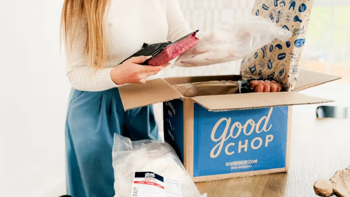 woman holding package of meat in front of good chop box