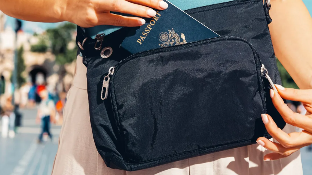 woman taking passport out of black crossbody bag