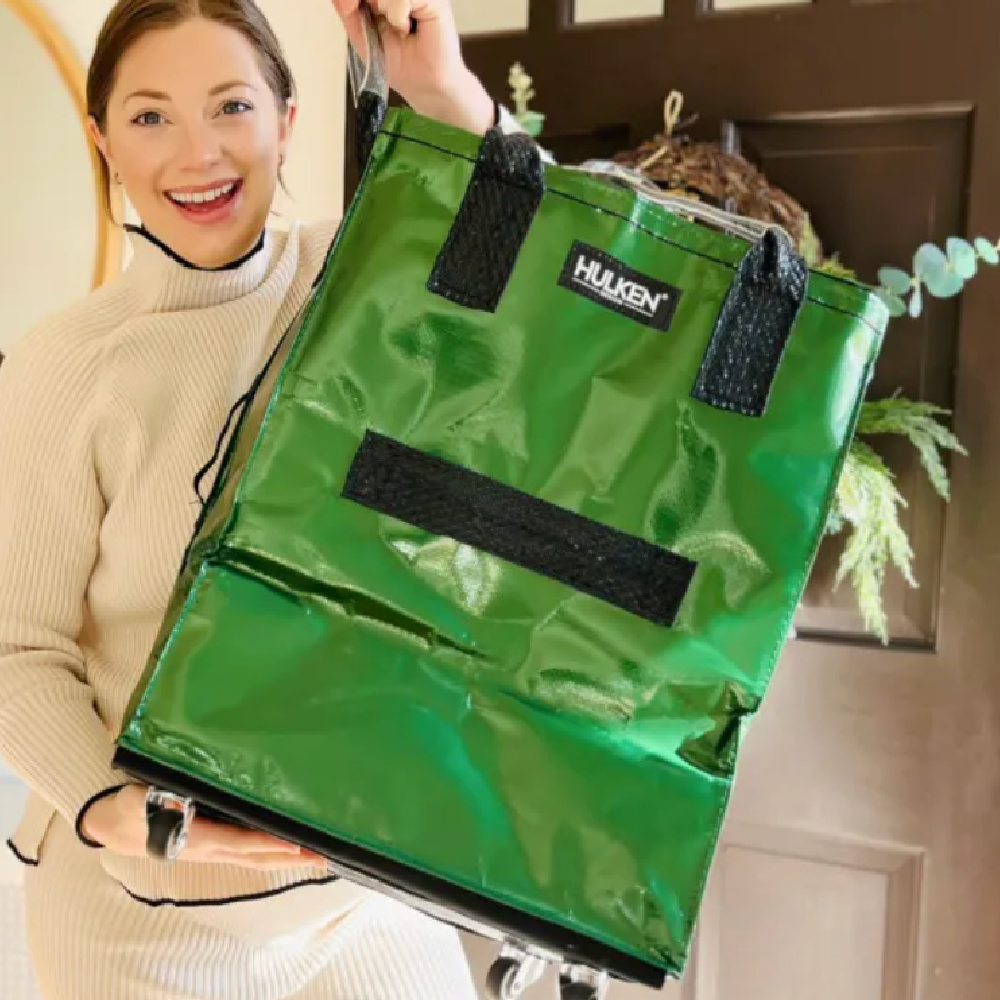 a woman holding a green bag with a plant in it