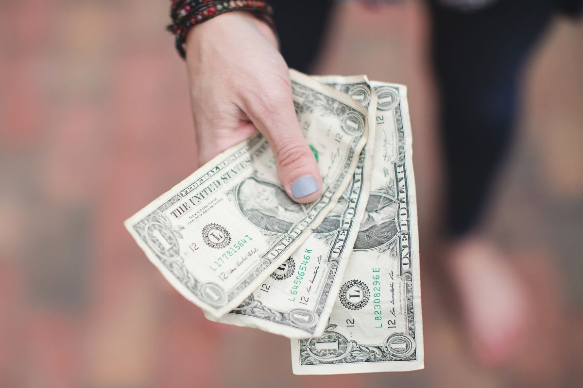 Women holding three dollar bills in hand