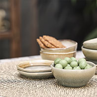 Bézs kerámia tálak egy asztalon gyümölcsökkel