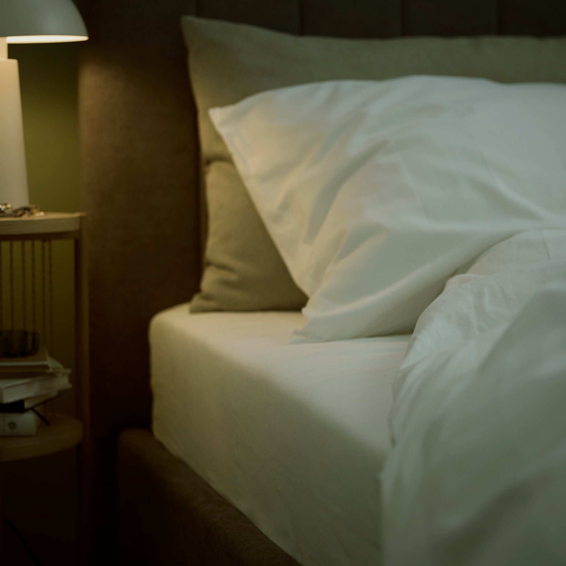 Egy fehér lepedővel takart matrac egy barna ágyon