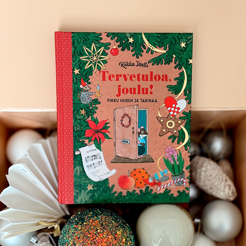 Kuvassa on keskellä etukansi suoraan kohti katsojaa Riikka Jäntin kirja ”Tervetuloa, joulu! Pikku hiiren 24 tarinaa”. Kirja lepää aseteltuna avoimen laatikon päälle, ja laatikon sisällä näkyy paperisia, kimaltelevia, valkoista lasia olevia sekä hopeisia joulukuusen koristeita.