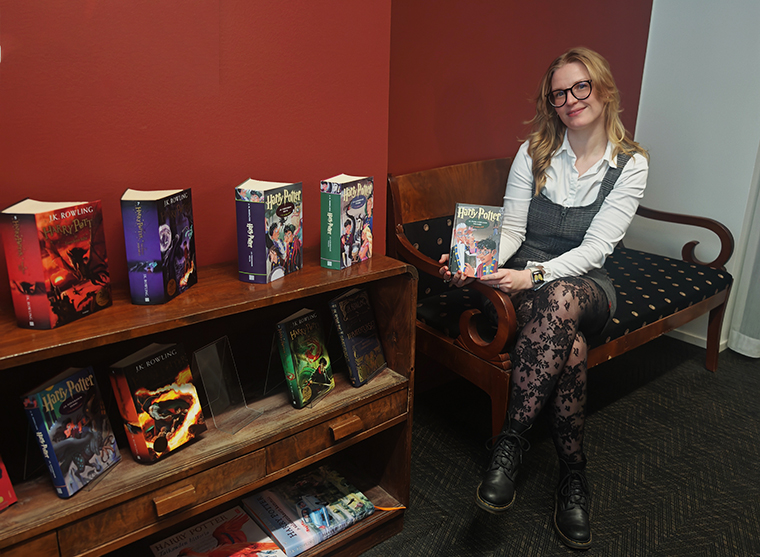 Kuvassa istuu sohvalla hymyilevä Maija Lang, joka pitelee Harry Potter -kirjaa.