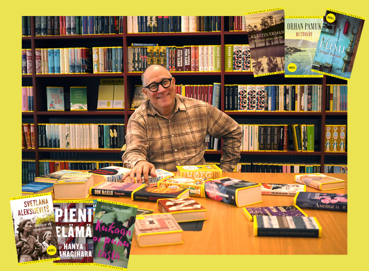 Graafikko Markko Taina kuvattuna istumassa pöydän ääressä takanaan hyllyriveittäin Keltaisen kirjaston teoksia.