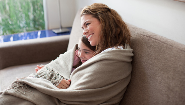 Vrouw en kind in een dekentje op de bank