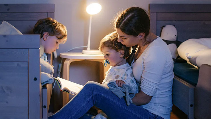 Vrouw met 2 kinderen boek aan het lezen