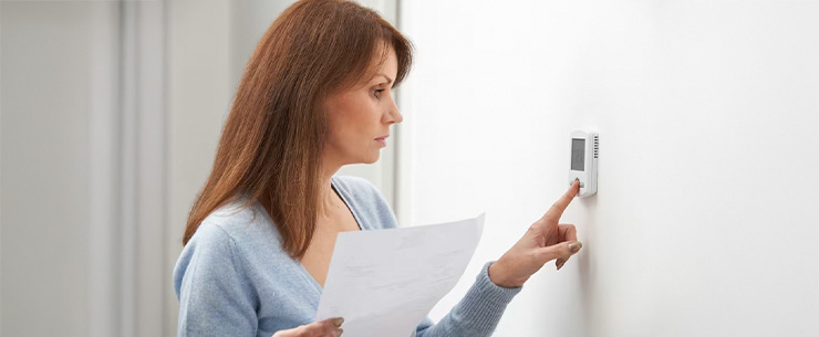Vrouw die drukt op de knoppen van een thermostaat
