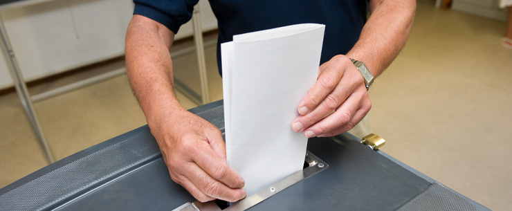 Iemand die een stemformulier in de stembus doet