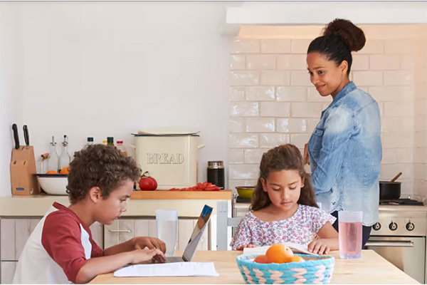 Vrouw in de keuken met twee kinderen aan de keukentafel