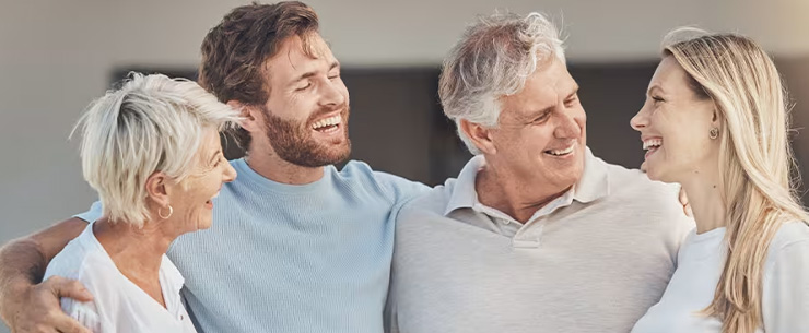 Vier volwassenen staan naast elkaar met de armen om elkaars schouders