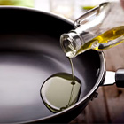 Iemand schenkt olie in een koekenpan