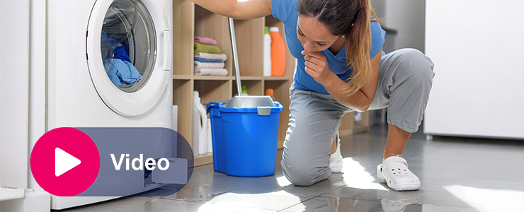 Vrouw kijkt naar kapotte wasmachine