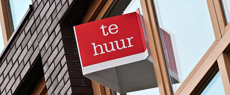 Gevel van een gebouw met een rood uithangbord waarop “te huur” staat.