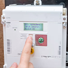 Hand die een knop indrukt op een digitale slimme energiemeter