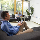 Man zit op de bank met een mobiel in zijn hand