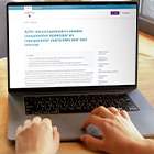 Persoon typt op laptop waarop webpagina van de ACM met artikel over aanpak internetproviders zichtbaar is.