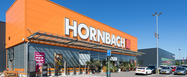 Gevel van bouwmarkt Hornbach met ingang en geparkeerde auto’s op parkeerterrein
