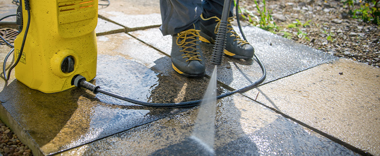 Waterstraal reinigt bestrating met groene aanslag.