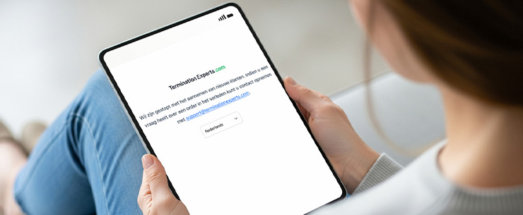 Persoon houdt een tablet vast met een melding dat de website TerminationExperts.com: Wij zijn gestopt met het aannemen van nieuwe klanten, indien u een vraag heeft over een order in het verleden kunt u contact opnemen.