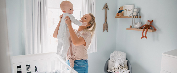 Moeder tilt haar baby uit bed