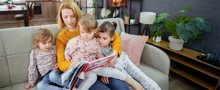 Vrouw op bank die aan het voorlezen is voor 3 kinderen