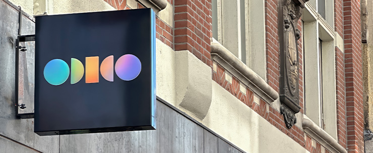 Uithangbord met Odido-logo aan een gebouwgevel.