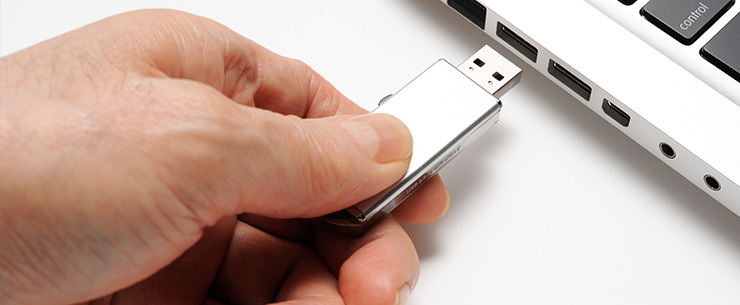 Hand steekt een USB-stick in een laptop