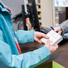 Persoon overhandigt een briefje aan een balie in een apotheek.