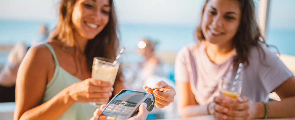 Twee personen betalen op een terras met een pinpas bij een betaalautomaat