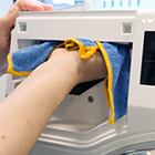 Hand maakt het zeepbakje van een wasmachine schoon met een doek