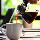 Koffie wordt uit een glazen kan in een mok geschonken