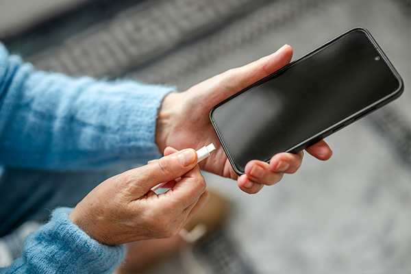 Handen sluiten een laadkabel aan op een smartphone