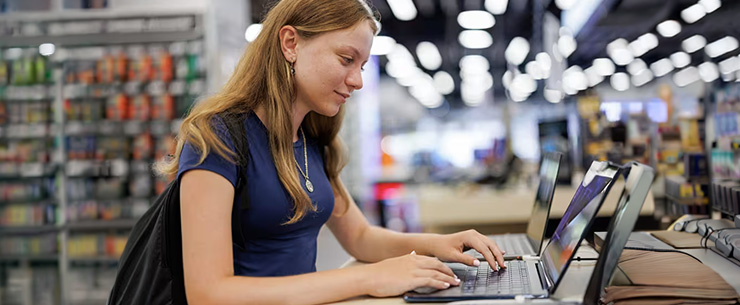 Jonge vrouw test een laptop in een winkel met elektronica