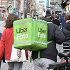 Twee maaltijdbezorgers met Uber Eats-tassen op straat