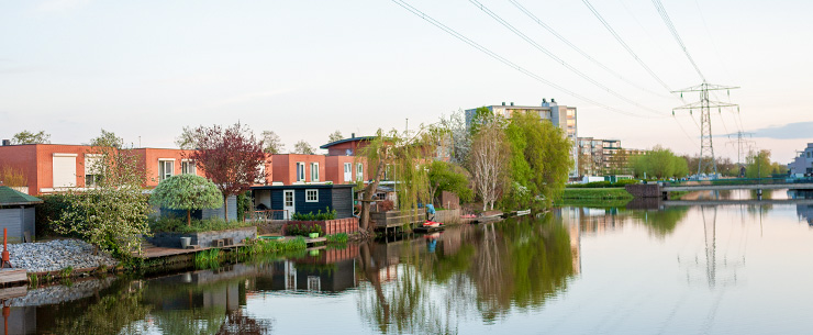 Woningen aan het water met hoogspanningsmasten op de achtergrond